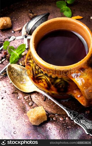 Hot herbal tea. Clay cup with herbal tea on a vintage background