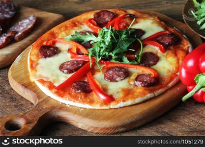 Hot homemade pizza with Pepperoni, paprica, rucola on wooden table .. Hot homemade pizza with Pepperoni, paprica, rucola on wooden table