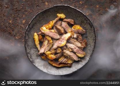 hot juicy sliced grill beef fillet steak meat in wabi sabi style plate on rusty texture background with somke, top view