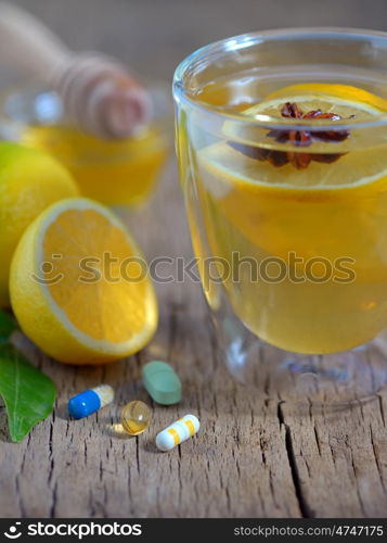 Hot lemon tea and pills on wooden table