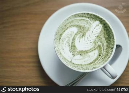 hot matcha green tea latte on wood table. delicious beverage