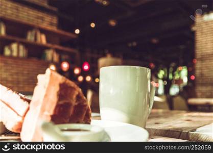 Hot mocha coffee in white cup and blurred waffle on the wooden table