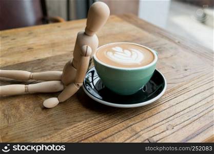 Hot mocha coffee or capuchino in the green cup lean by wood man on the wooden table