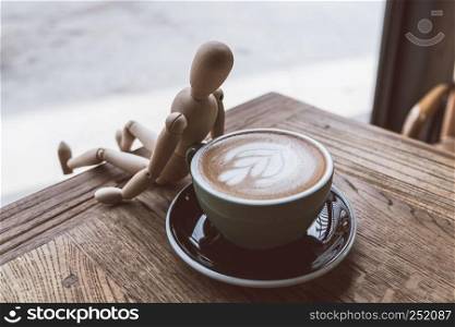 Hot mocha coffee or capuchino in the green cup lean by wood man on the wooden table