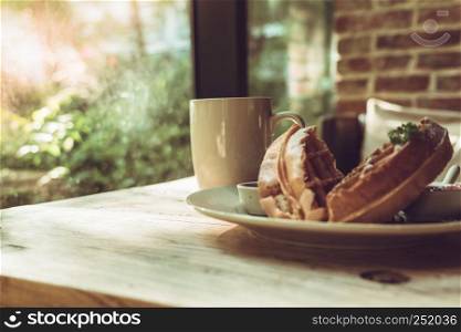 Hot mocha coffee or capuchino with 2 pieces of waffle on the wooden table