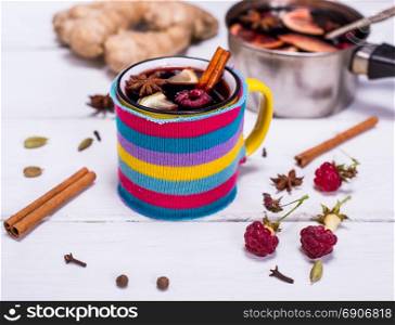 hot mulled wine in a mug and spices on a white wooden background