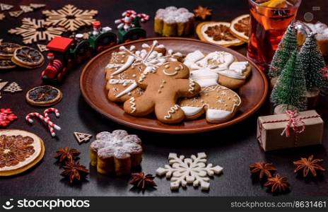 Hot mulled wine with a slice of orange, with cinnamon, cloves and other spices with chocolate muffins and Christmas decorations on a dark concrete background. Hot mulled wine with a slice of orange, with cinnamon, cloves and other spices