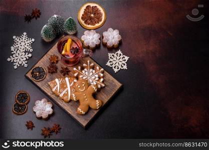 Hot mulled wine with a slice of orange, with cinnamon, cloves and other spices with chocolate muffins and Christmas decorations on a dark concrete background. Hot mulled wine with a slice of orange, with cinnamon, cloves and other spices