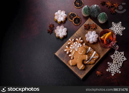 Hot mulled wine with a slice of orange, with cinnamon, cloves and other spices with chocolate muffins and Christmas decorations on a dark concrete background. Hot mulled wine with a slice of orange, with cinnamon, cloves and other spices