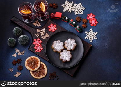 Hot mulled wine with a slice of orange, with cinnamon, cloves and other spices with chocolate muffins and Christmas decorations on a dark concrete background. Hot mulled wine with a slice of orange, with cinnamon, cloves and other spices