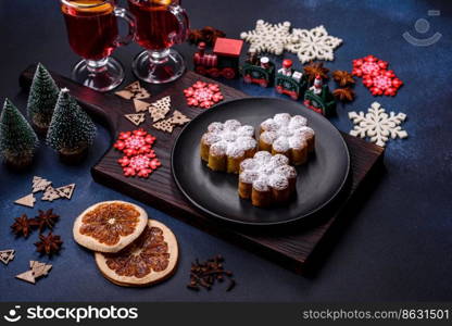 Hot mulled wine with a slice of orange, with cinnamon, cloves and other spices with chocolate muffins and Christmas decorations on a dark concrete background. Hot mulled wine with a slice of orange, with cinnamon, cloves and other spices