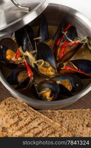 hot mussels in metal pan with cover on brown napkin