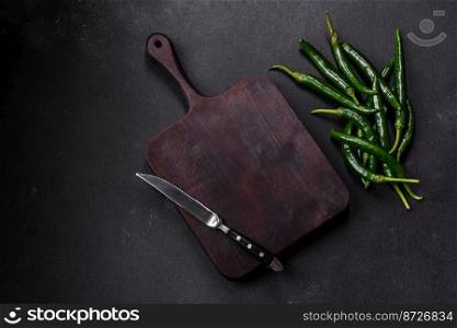 Hot pepper of green color on a dark concrete background. Mexican cuisine dishes. Hot pepper of green color on a dark concrete background