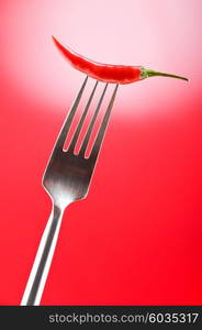 Hot pepper on the fork against colour background