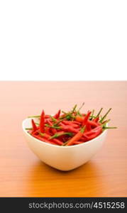 Hot peppers in the plate on wooden table