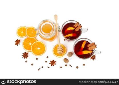 Hot red mulled wine, bee honey, slices of oranges and spices isolated on white background. Flat lay, top view. Free space for text.