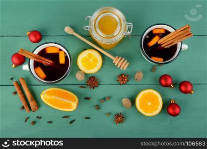 Hot red mulled wine on wooden background with christmas spices, orange slice, anise and cinnamon sticks, close up. Flat lay, top view.