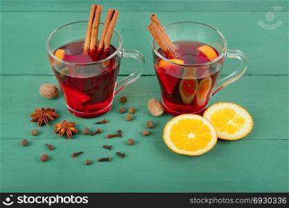 Hot red mulled wine on wooden background with christmas spices, orange slice, anise and cinnamon sticks, close up.