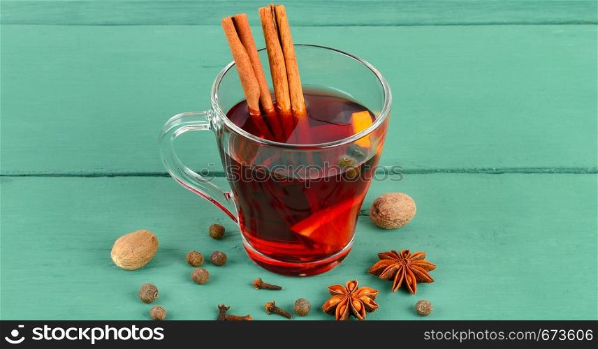 Hot red mulled wine on wooden background with spices, orange slice, anise and cinnamon sticks. Wide photo.