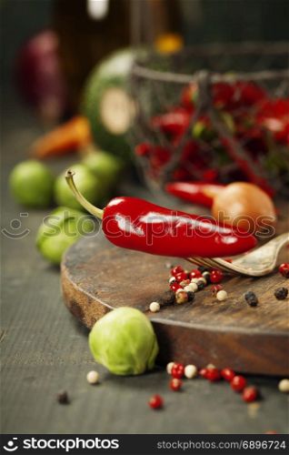 Hot red pepper and ingredients for cooking on rustic background