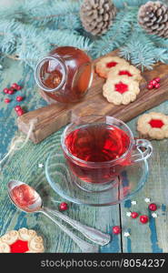 Hot red tea in a transparent cup, jam and cookies on a background of Christmas decorations