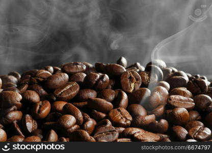 Hot roasted coffee beans and steam on black. Hot roasted coffee beans