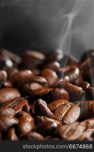 Hot roasted coffee beans and steam on black. Hot roasted coffee beans