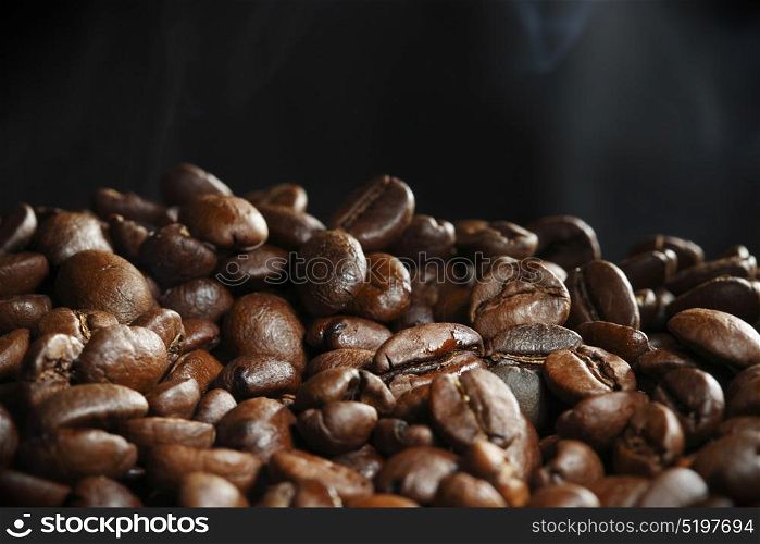 Hot roasted coffee beans. Hot roasted coffee beans and steam on black