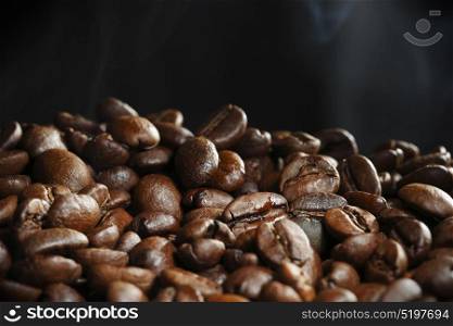 Hot roasted coffee beans. Hot roasted coffee beans and steam on black