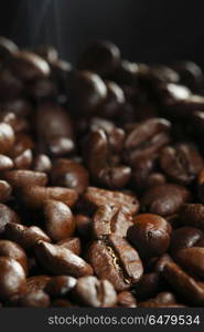 Hot roasted coffee beans. Hot roasted coffee beans and steam on black