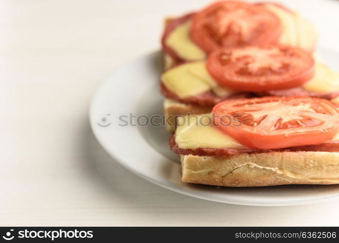 hot sandwiches with melted cheese sausage, salami and tomatoes