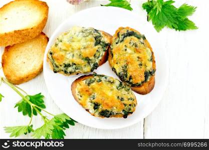 Hot sandwiches with nettles and cheese on slices of wheat bread in a plate on a wooden board background from above