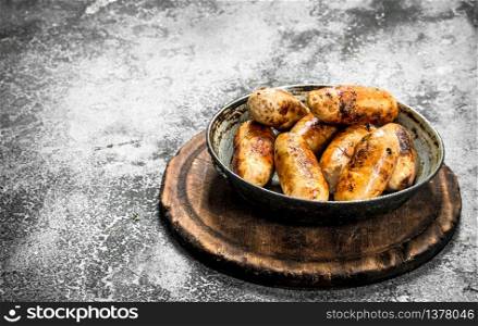 Hot sausages in a frying pan. On a rustic background.. Hot sausages in a frying pan.