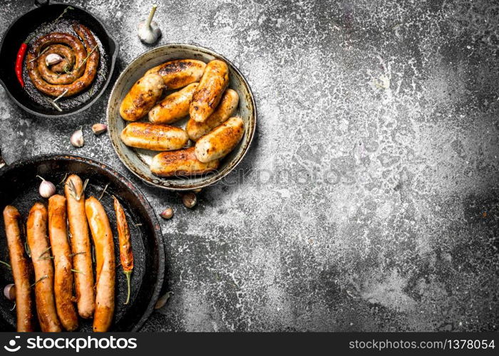 Hot sausages in a frying pan. On a rustic background.. Hot sausages in a frying pan.