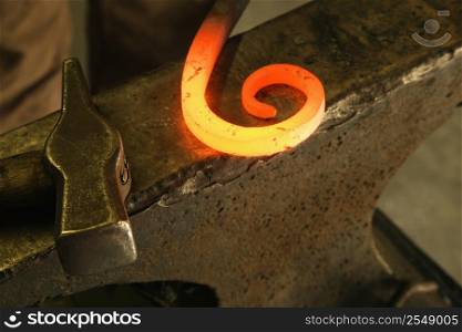 Hot shaped metal laying on anvil with hammer.