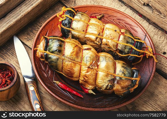 Hot smoked mackerel roll.Delicious smoked fish on plate. Smoked mackerel on wooden background
