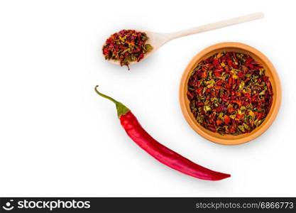 Hot spices in a cup and spoon and a large chili pepper on a white background