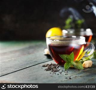 Hot tea cup with mint and sugar on rustic background