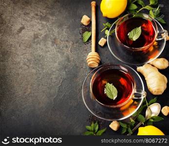 Hot tea cups with mint, lemon and sugar on rustic background