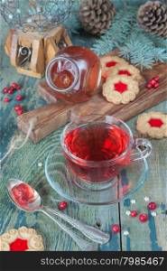 Hot tea in a transparent cup, jam and cookies on a background of Christmas decorations
