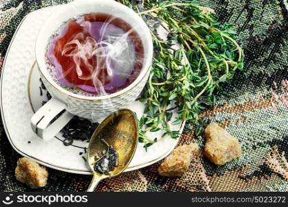 Hot tea with thyme. Porcelain Cup on saucer with hot tea medicinal herbs