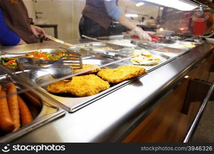Hot trays with cooked food close-up in dining room