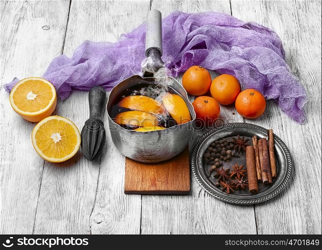Hot wine with oranges. Warmed red wine in retro scoop with spices