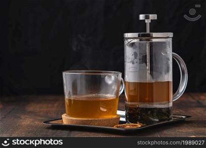 Hot winter tea served with a french press on a wooden floor.