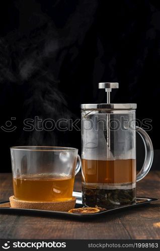 Hot winter tea served with a french press on a wooden floor.