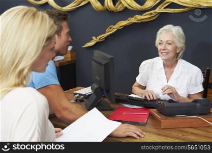 Hotel Receptionist Helping Couple To Check In
