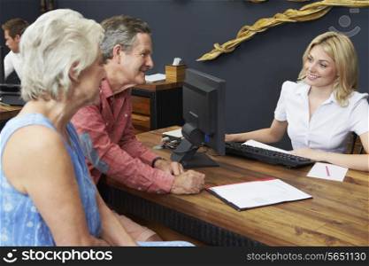 Hotel Receptionist Helping Senior Couple To Check In