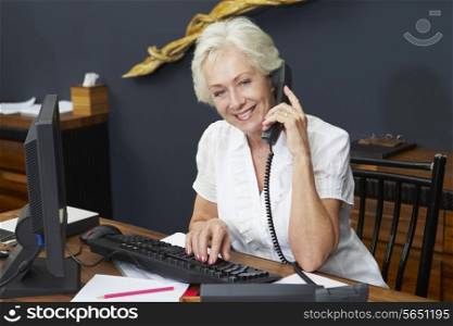 Hotel Receptionist Using Computer And Phone