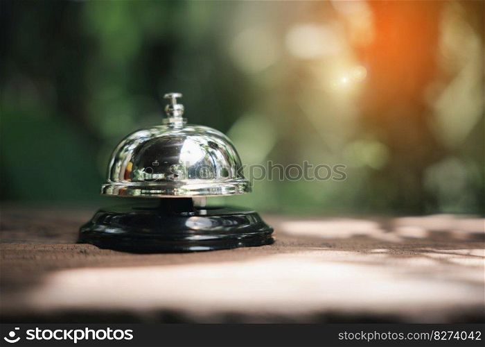 Hotel ring bell. Vintage bell to call staff outdoor in garden with green leaf, Closeup of silver service restaurant bell on wooden counter desk