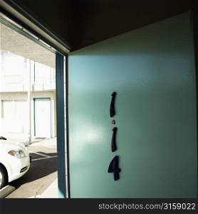 Hotel room door, number 114 and white car